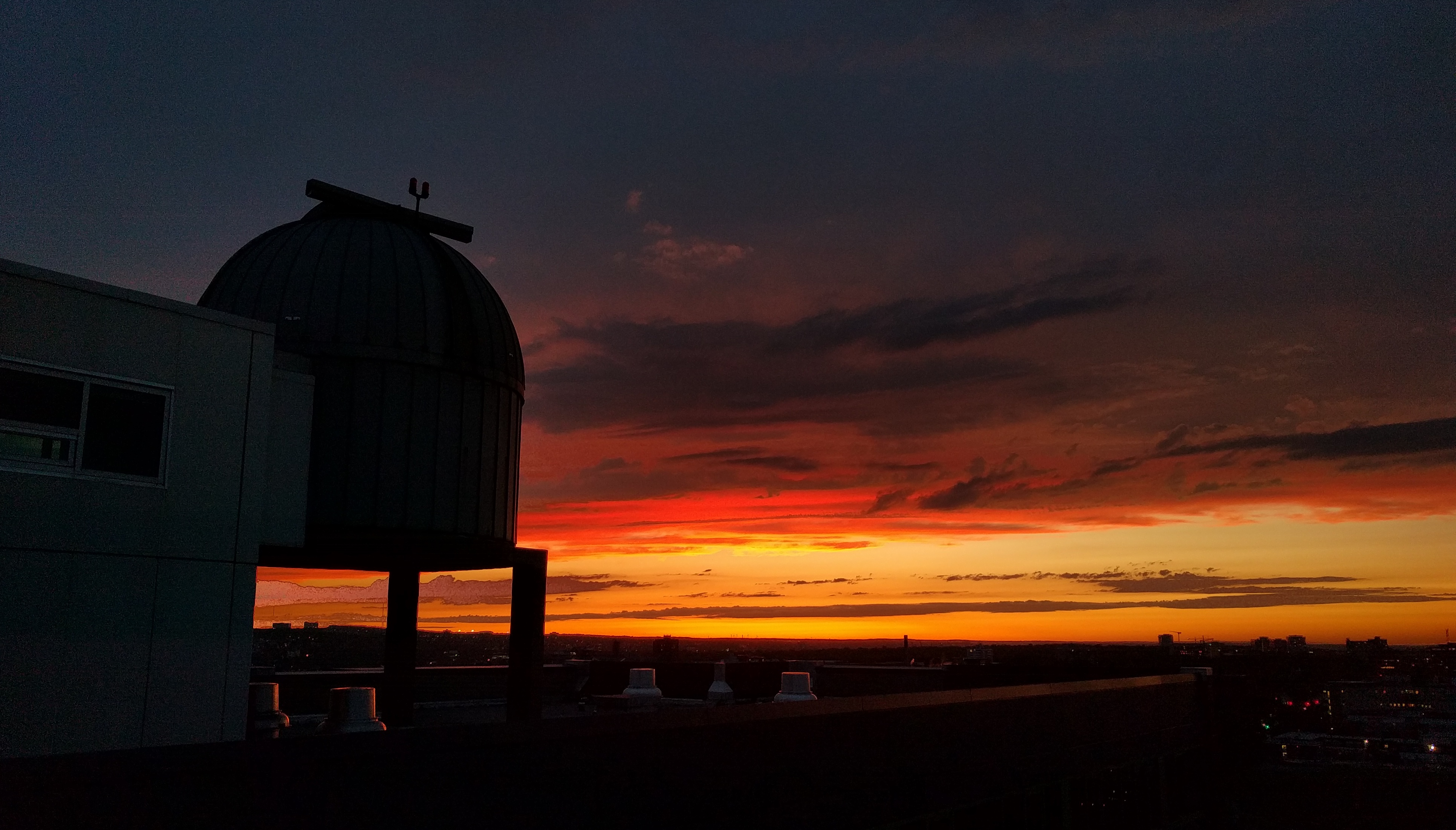 Dark image of the Burke-Gaffney Observatory dome against a dark sunset.