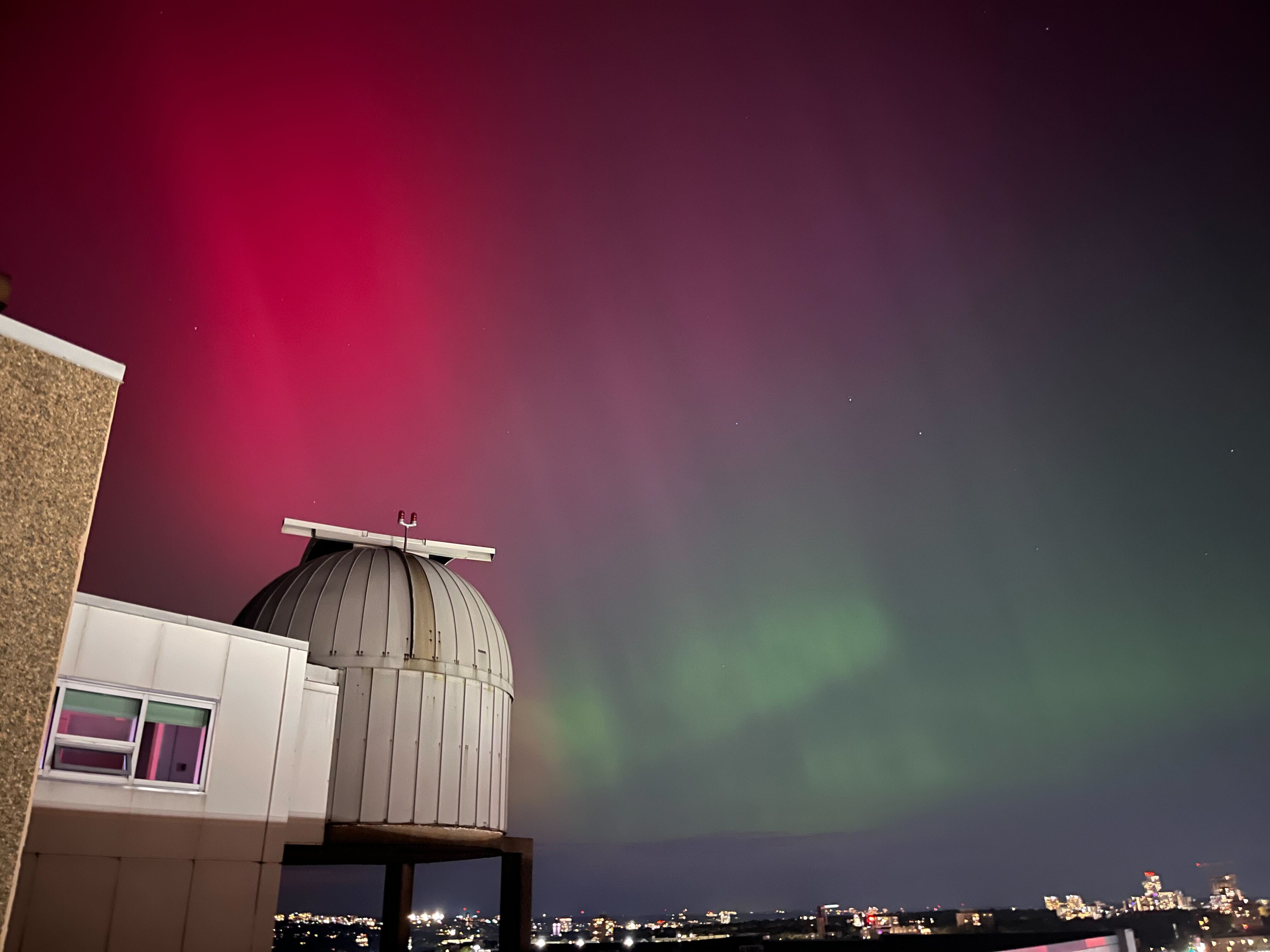 Image of the colourful aurora (reds and greens) on the sky behind the Burke-Gaffney Observatory dome.